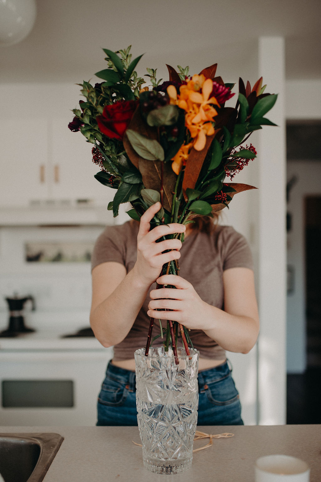 A woman holds a bouquet of flowers in front of her face.