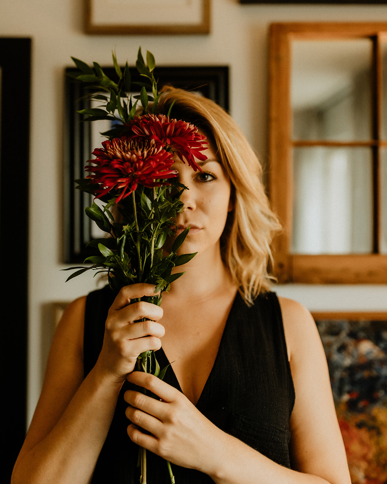 Lauren Hughes holding red flowers in front of her face.